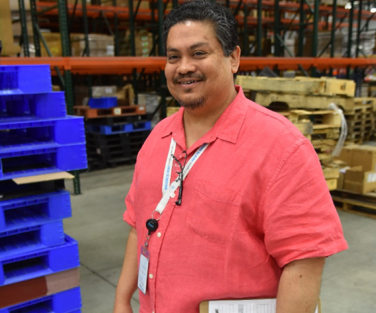 A warehouse employee standing and smiling